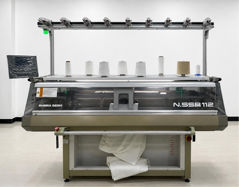 Close-up: Shima Seiki computerized flat-knit machine knitting a panel
